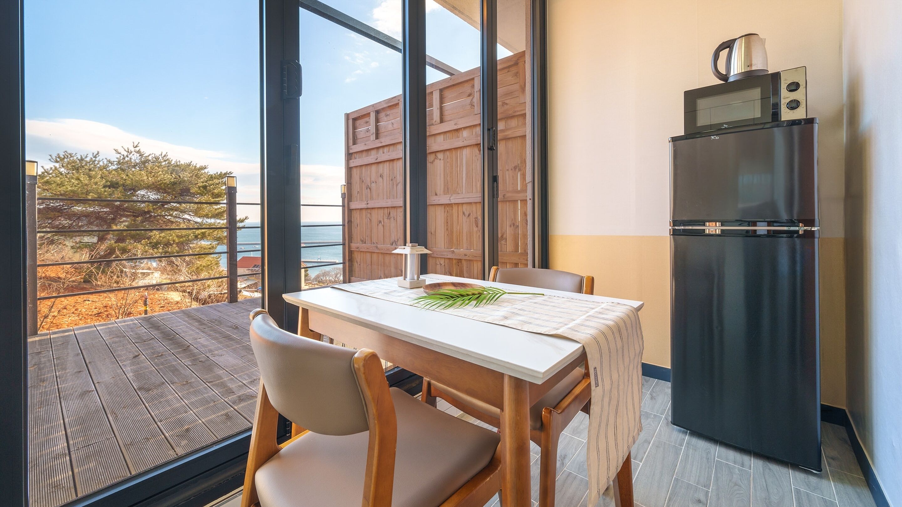 Una cocina compacta con refrigerador, una mesa de comedor con sillas y vista al exterior.