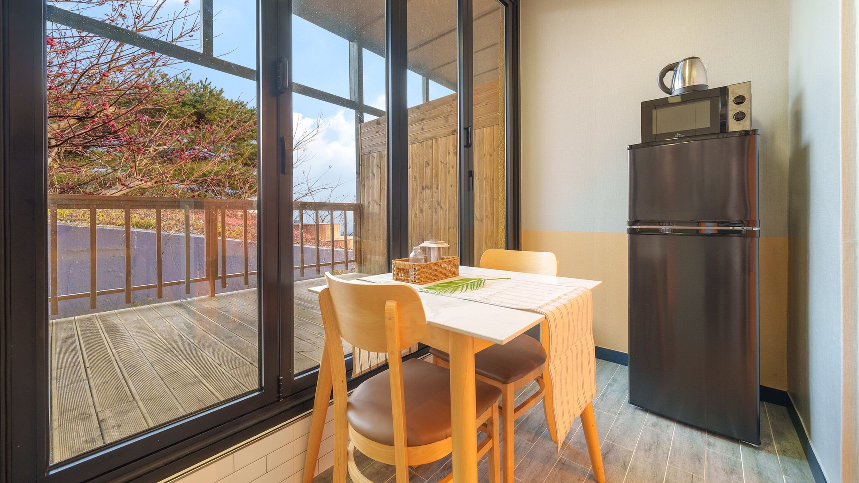 A small kitchen with a refrigerator, microwave, and a dining table with chairs.