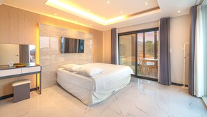 A modern hotel room with a large bed, a desk with a mirror, and a sliding glass door leading to an outdoor area. - Namhae Onview Pension (Namhae)