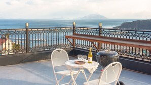 A balcony with a table and chairs, a bottle of wine, and a large pot. - Namhae Onview Pension (Namhae)