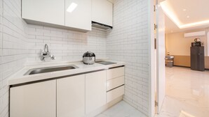 A modern kitchen with white cabinetry, a stainless steel sink, and a compact island. - Namhae Onview Pension (Namhae)