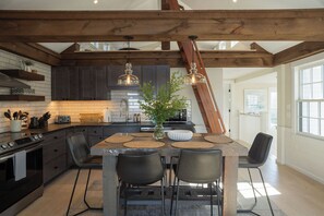 A modern kitchen with dark cabinets, a wooden ceiling, and a central island with chairs.