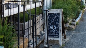 Une devanture de magasin sur le thème de la côte, avec une enseigne en bois, un panneau noir et une clôture blanche à piquets.