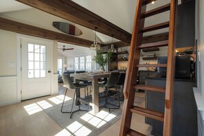 A spacious kitchen with a dining area, wooden beams, and a large window allowing natural light.