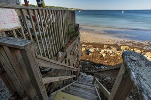 A wooden staircase leading to a beach with a sign indicating private property.