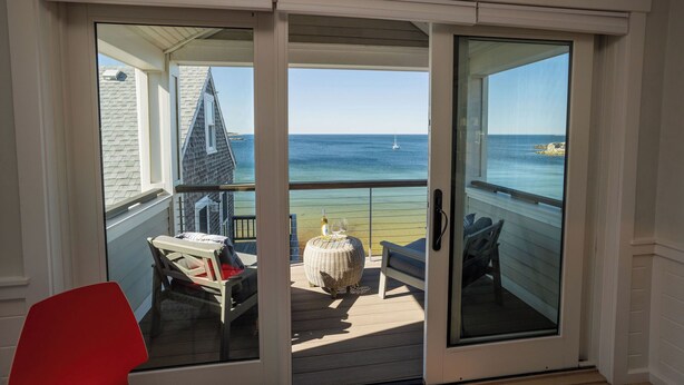 Un balcon avec vue sur la mer, une chaise, une table et un banc.