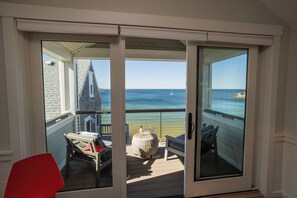 Een balkon met uitzicht op zee, een stoel, een tafel en een bank.