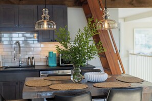 Una cocina con una isla de madera, un florero con plantas verdes y lámparas colgantes.