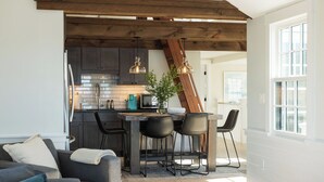 Une cuisine moderne avec des meubles de couleur sombre, un plafond en bois et des luminaires suspendus.