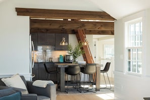 A modern kitchen with dark cabinets, a wooden ceiling, and pendant lighting.