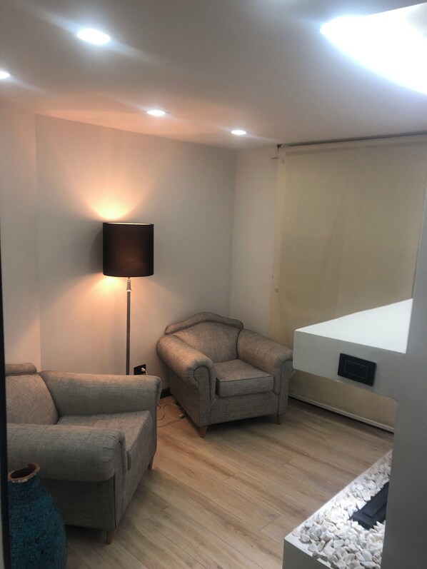 A modern living room with a sofa, armchair, and floor lamp.