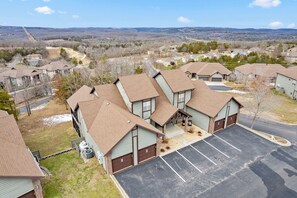 A residential area with houses, a parking lot, and a hilly landscape in the background. - Townhouse at Stonebridge Near Silver Dollar City_Free Tickets _Golf Course_Outdoor Pool (Branson West)