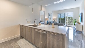 A modern kitchen with a large island, stainless steel appliances, and a view to a balcony.