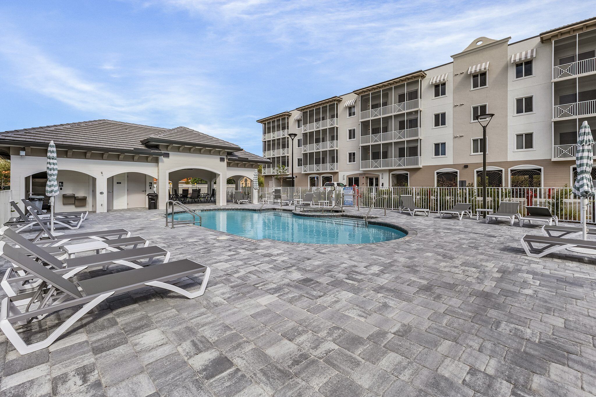 A pool area with lounge chairs and a building with balconies.