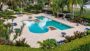 A swimming pool with a unique shape surrounded by lounge chairs and palm trees.
