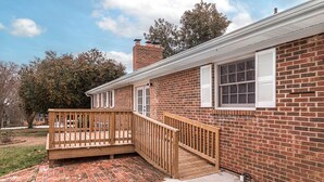 A brick house with a wooden deck and a small porch.
