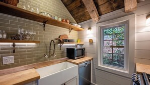 Una cocina con encimera de madera, armarios blancos, lavavajillas integrado y ventana con vistas a zonas verdes.