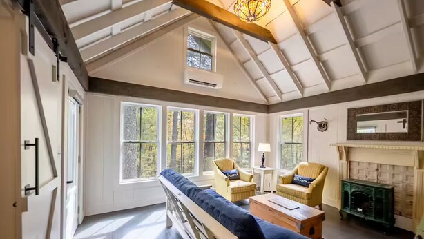 Una habitación amplia con techo alto, ventanas grandes, chimenea y un banco.