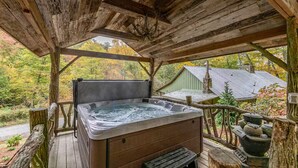 Un jacuzzi en un pabellón de madera con vistas a una casa y follaje otoñal.