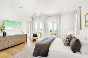 Ein Schlafzimmer mit Bett, Kommode, Fernseher und Blick ins Freie.