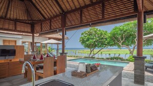 A modern kitchen with a large island, a built-in sink, and a view of the ocean. - The Manik Kalisada (Seririt)