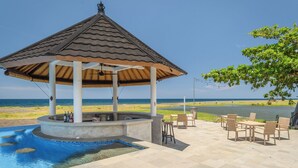 A gazebo with a tiled roof overlooking a pool and beach. - The Manik Kalisada (Seririt)