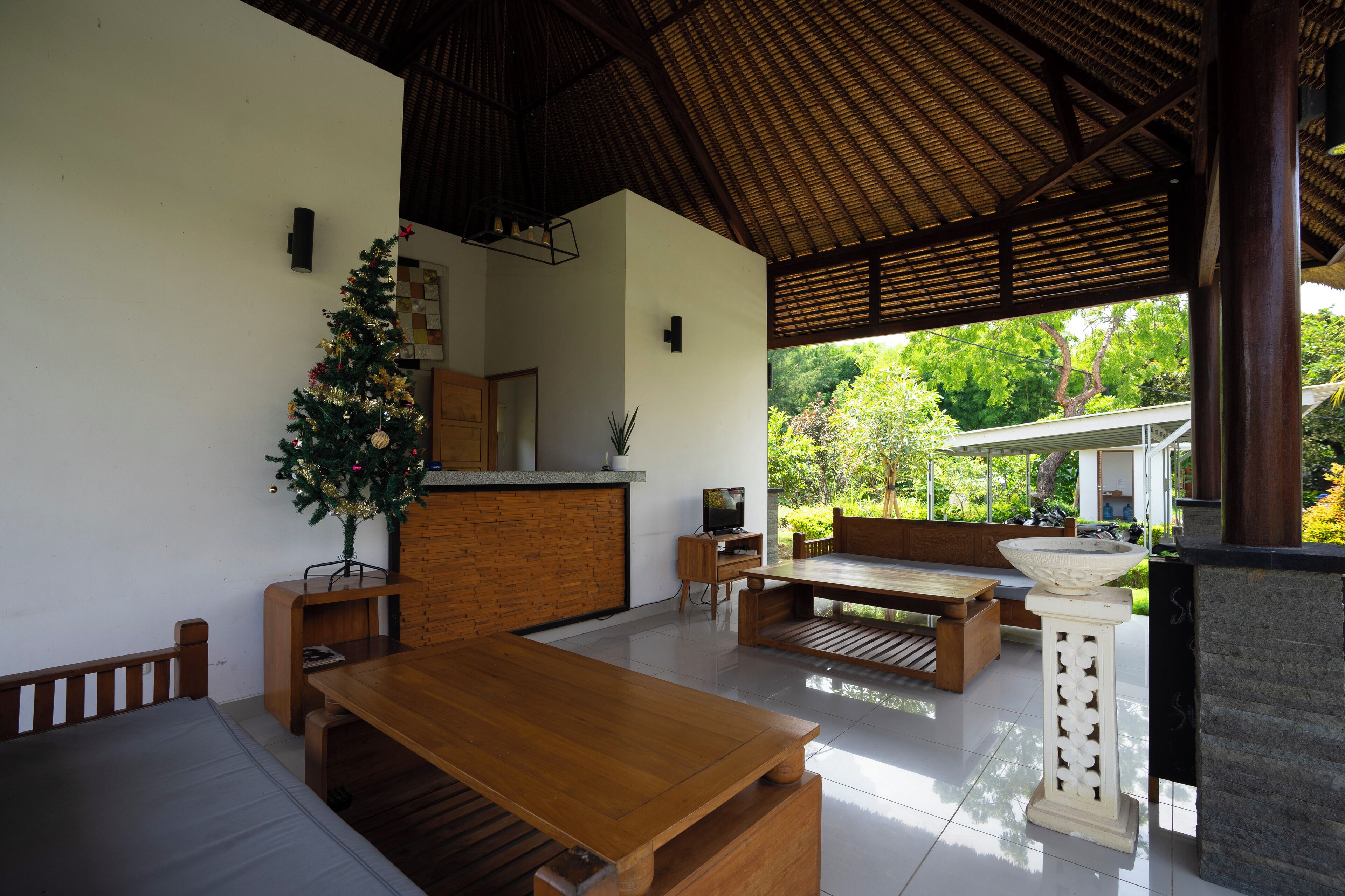 Un espacio de sala de estar moderno y abierto con una mesa de comedor de madera, un sofá y un árbol de Navidad.
