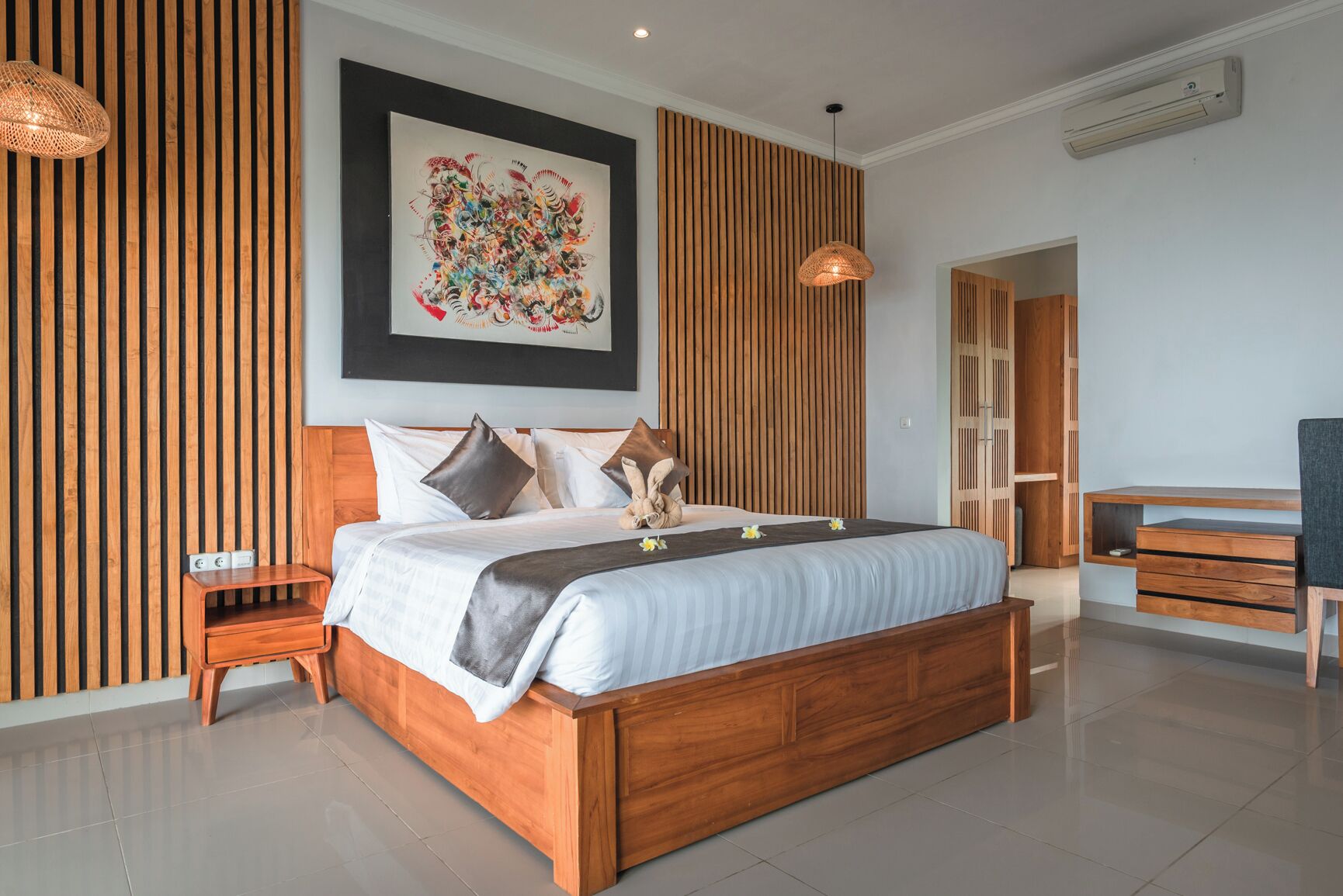 Una camera da letto moderna con un letto di legno, un grande quadro astratto e una scrivania con cassetti.