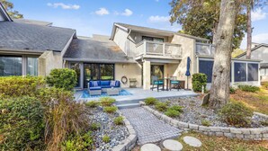 A modern house with a patio area, a covered seating area, and a stone pathway.