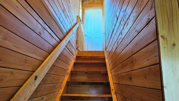 Una escalera de madera que lleva a una puerta al final de una cabaña.
