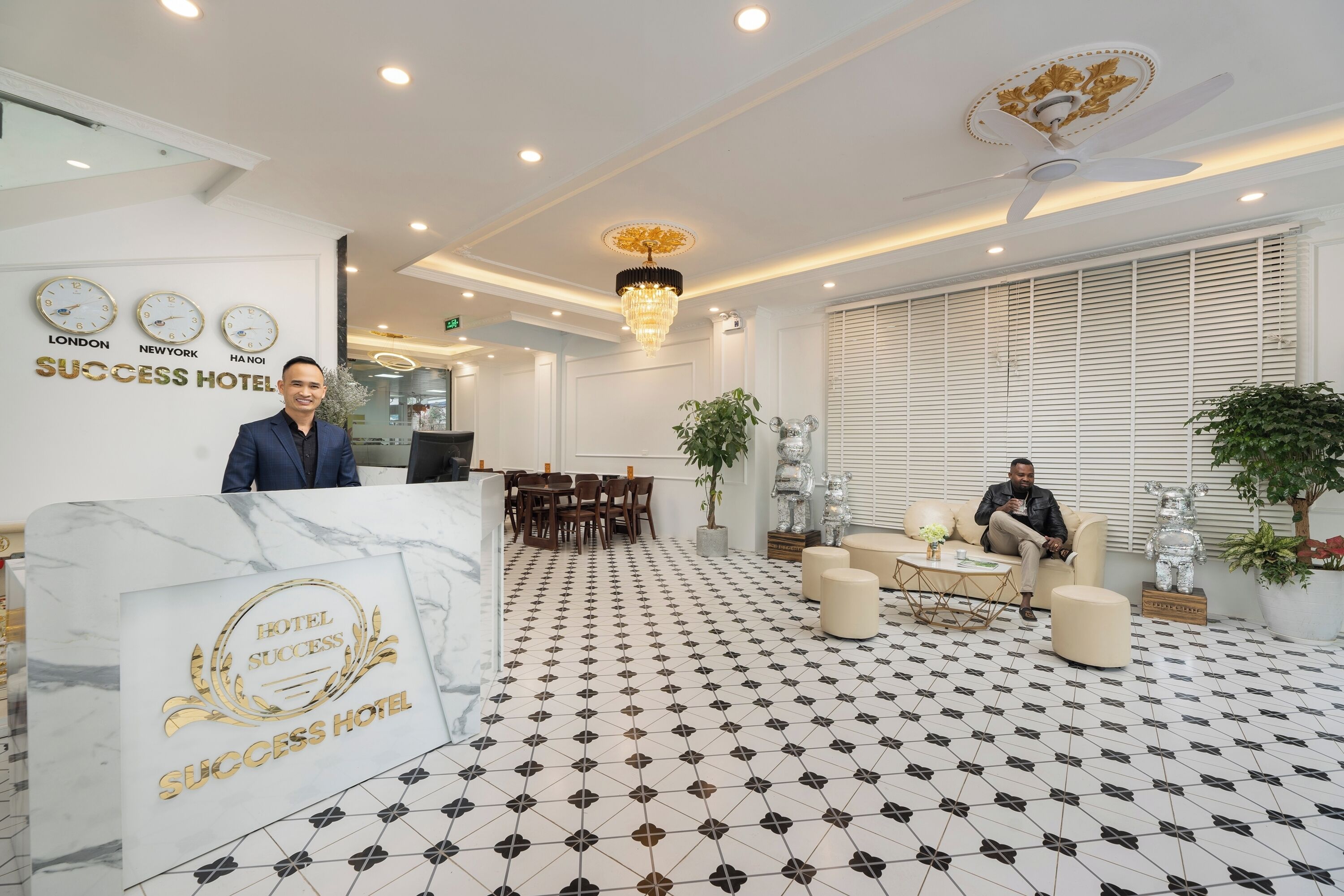 A reception area with a marble counter, clocks, and a chandelier.