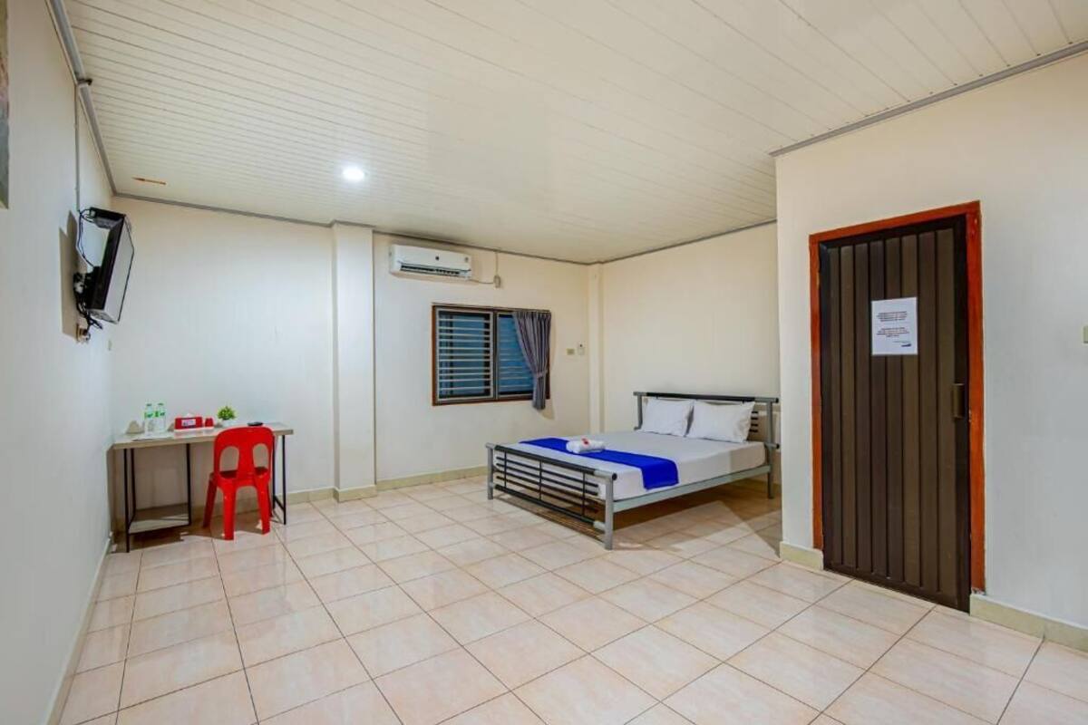 Una habitación con cama, escritorio, silla y puerta.