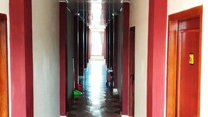 Un corridoio con pavimento a scacchi, pareti rosse e porte su entrambi i lati.