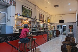 A modern hotel lobby with a bar area, artwork on the walls, and a seating area with a unique elephant-shaped table. - Hotel Bambu Kuning (Bandar Lampung)
