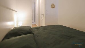 A bedroom with a bed, a nightstand, and a wall-mounted light fixture.