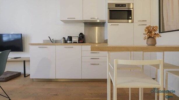 A modern kitchen with white cabinets, a stainless steel oven, and a coffee maker.