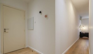Ein Flur mit Holzboden, einer geschlossenen Tür und einer Wandleuchte.