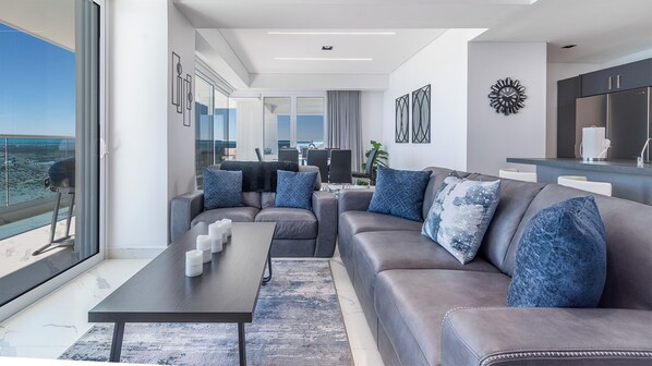 Un salón moderno con un sofá gris, una mesita de centro y vista al océano.