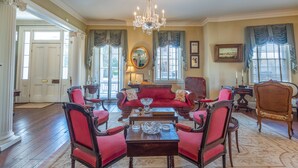 Un comedor formal con candelabro, sillas tapizadas en rojo, una mesa de madera y un espejo grande en la pared.