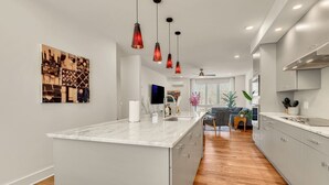 Uma cozinha moderna com bancada de mármore, iluminação pendente e uma ilha central.