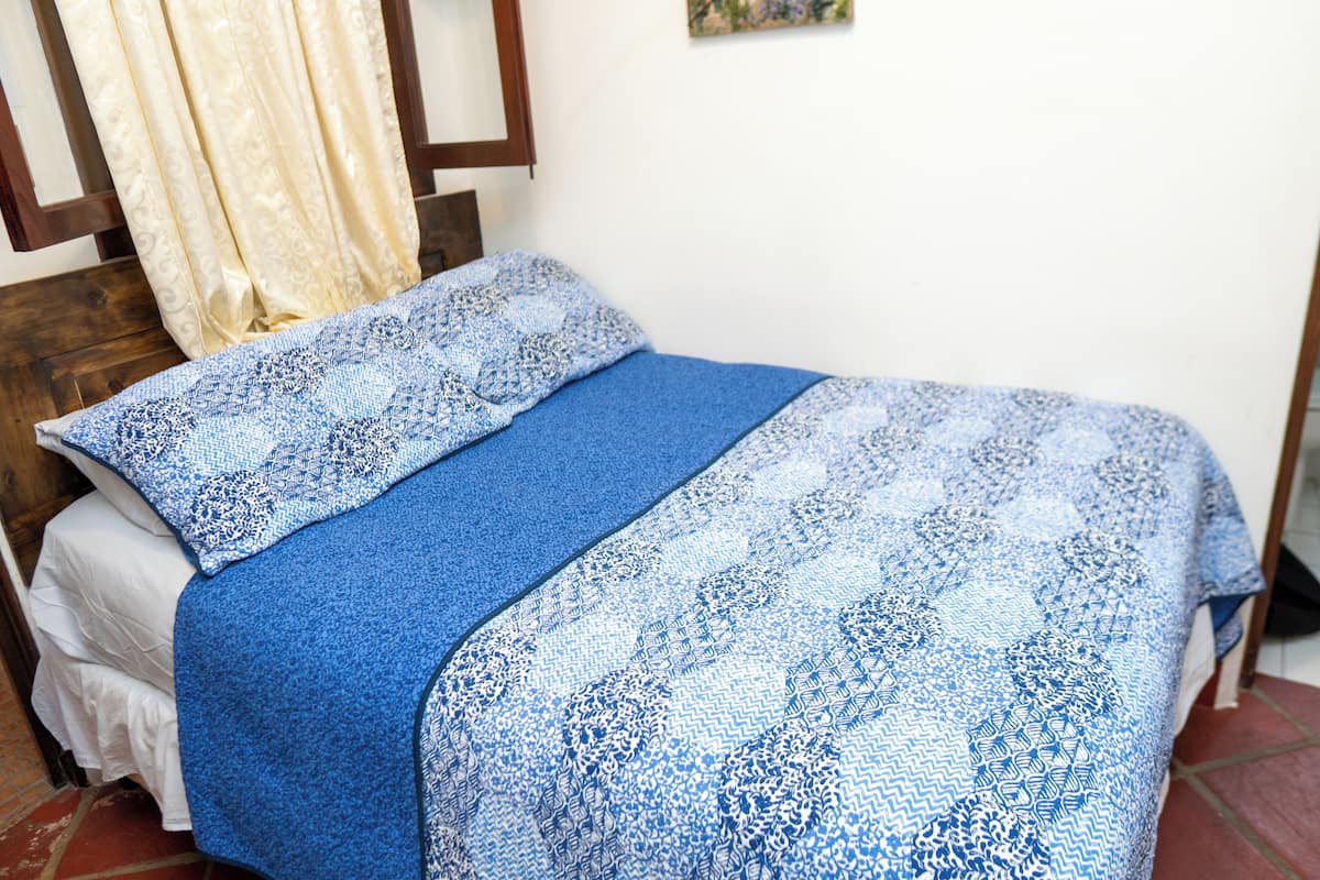 A bed with a blue and white patterned bedspread and matching pillow.