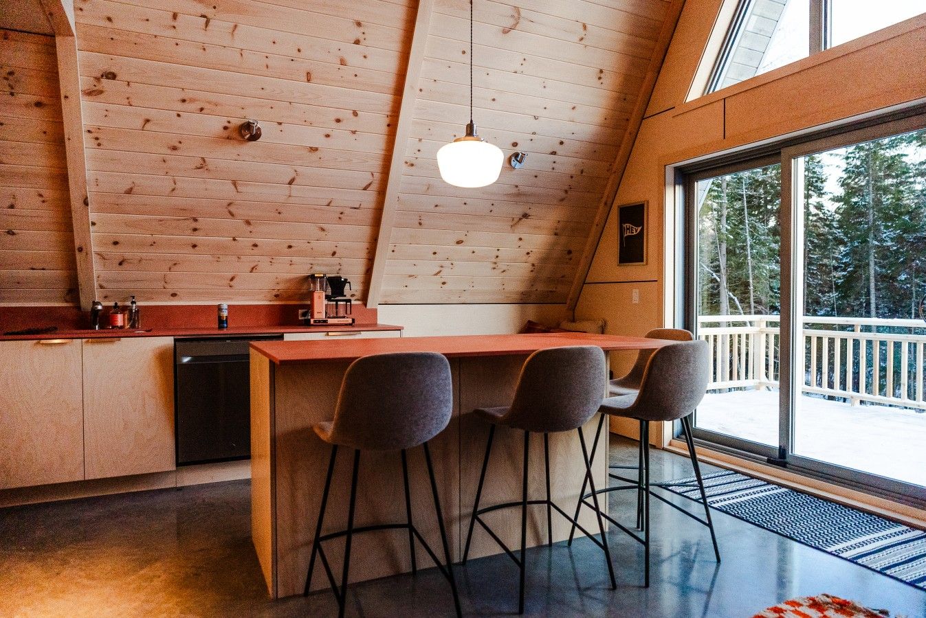 Une cuisine moderne avec des murs en bois, un coin bar et une vue sur une terrasse enneigée.