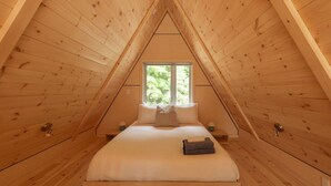 A small, wooden attic bedroom with a single bed, a window, and a sloped ceiling. - Canadian Classic | Spa • Sauna • Fire • Forest (Sainte-Lucie-des-Laurentides)