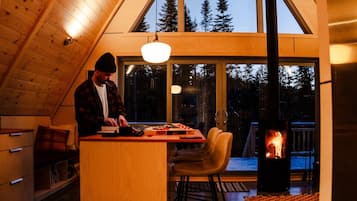 L’intérieur chaleureux d’un chalet avec un plafond en bois, un coin repas comprenant une table et des chaises, et une cheminée.