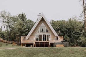 Eine moderne A-Form-Hütte mit einer Holzterrasse und einem großen Schiebeglastür.