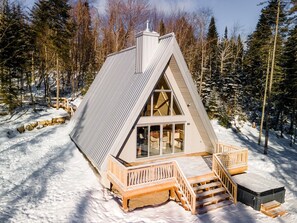 A cabin with a sloped roof, large windows, and a wooden deck.