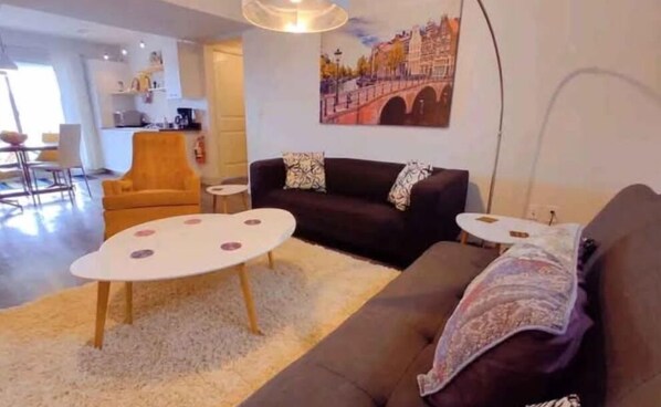 A living room with a sofa, two small side tables, a coffee table, and a painting on the wall. - Charming 2-bedroom suite in Lake Country with AC, WiFi.  (Lake Country)