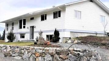 Une maison à deux étages avec un mur de pierre à l’avant, un garage et une allée.