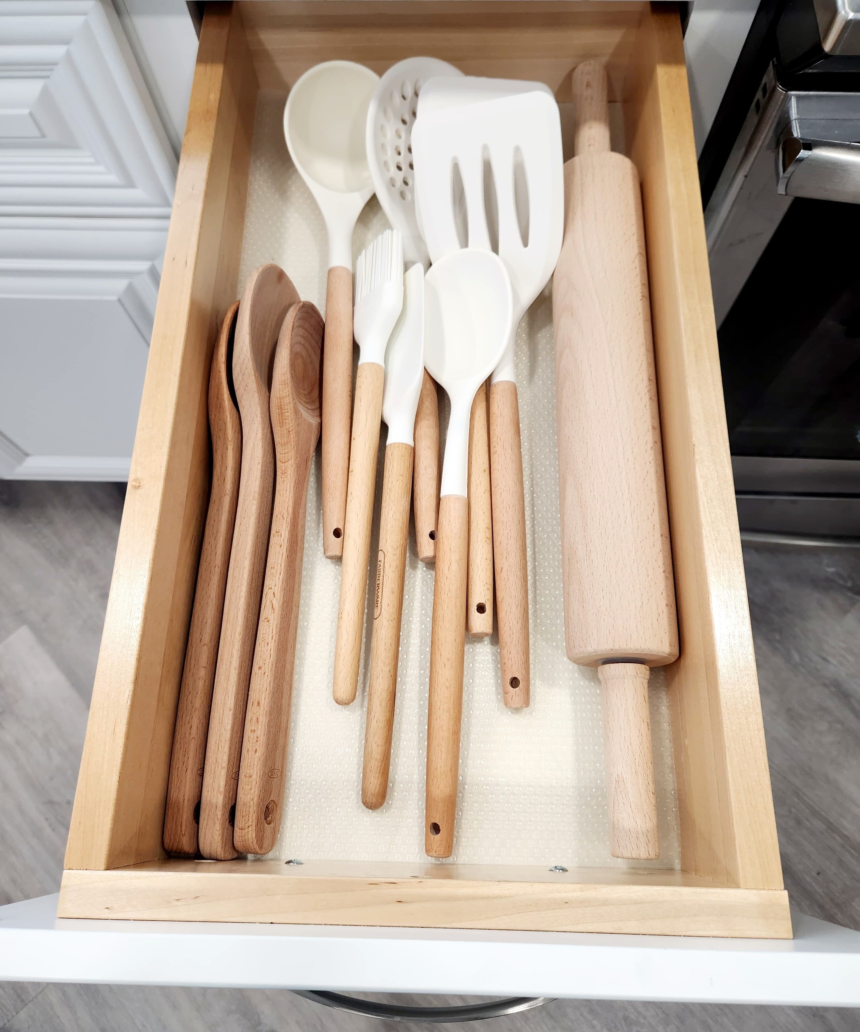 A drawer containing various kitchen utensils including wooden spoons, spatulas, and a rolling pin.