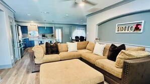 A modern living room with a sectional sofa, a coffee table, and a dining area in the background. - Spacious 4-bedroom house with Hot Tub in beautiful Balch Springs with AC, WiFi (Balch Springs)